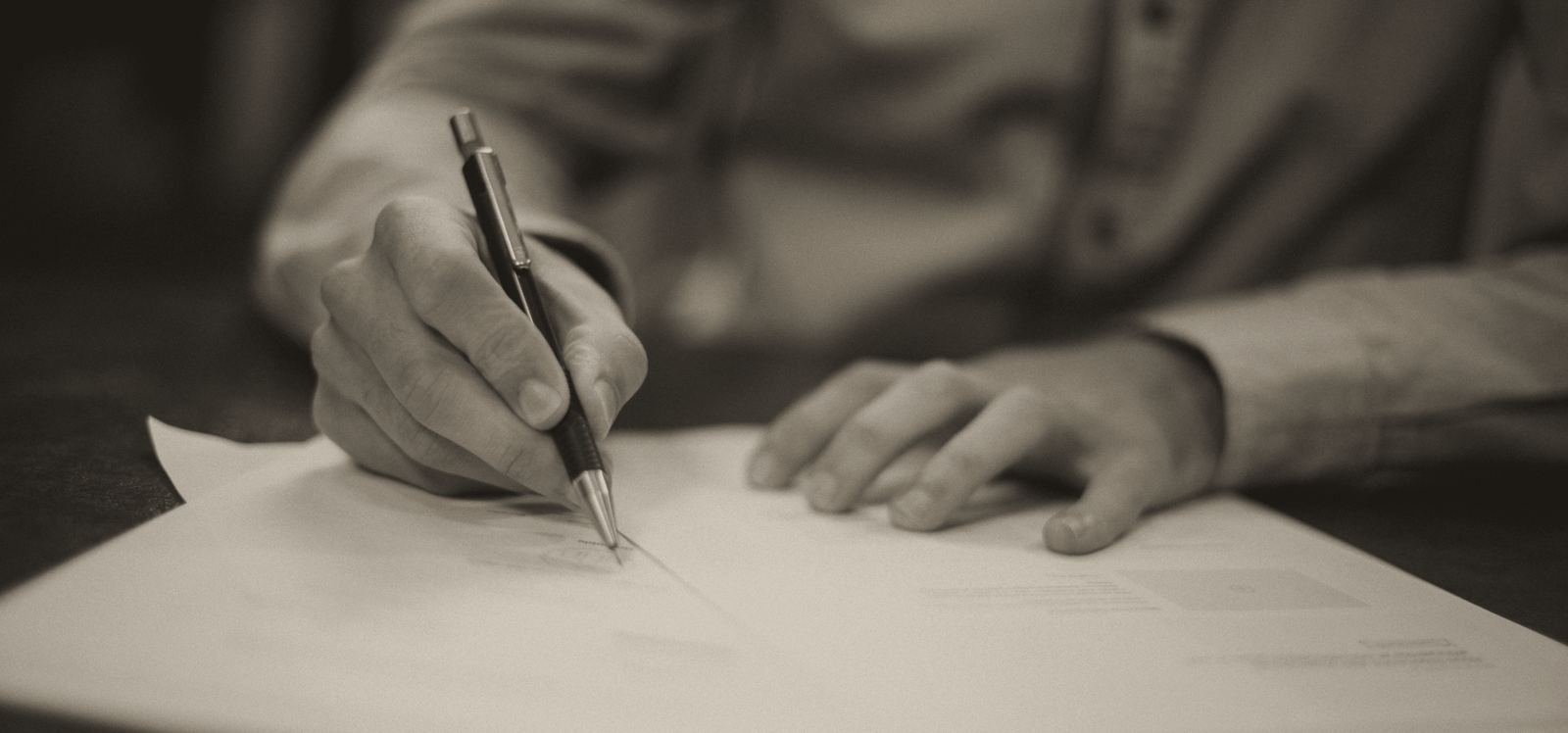 A hand signing a document